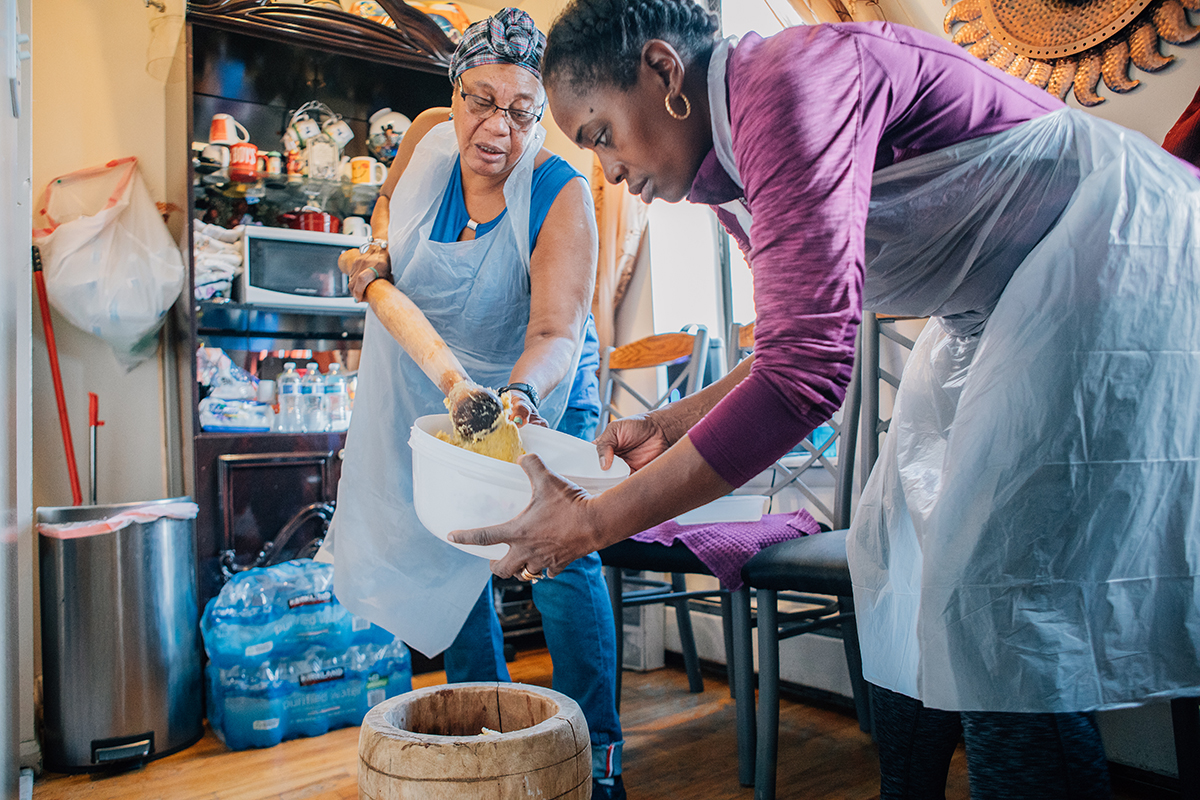 Mashing the boiled plantains, “hudutuing,{quote} is traditionally done by men. However, here, Yolanda and Sylvia take turns huduting.