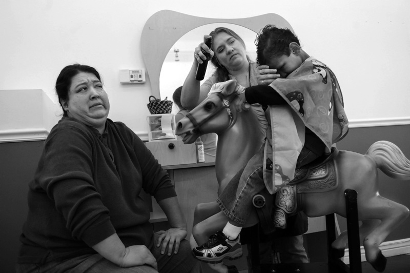 Lelana Fayre watches as her son, Pandu Fayre has his first haircut with his new parents at Lollilocks Kids Salon by Tobie Booth Friday 05/01/09 the day before the celebration of his sixth birthday. Photo by Matt McClain