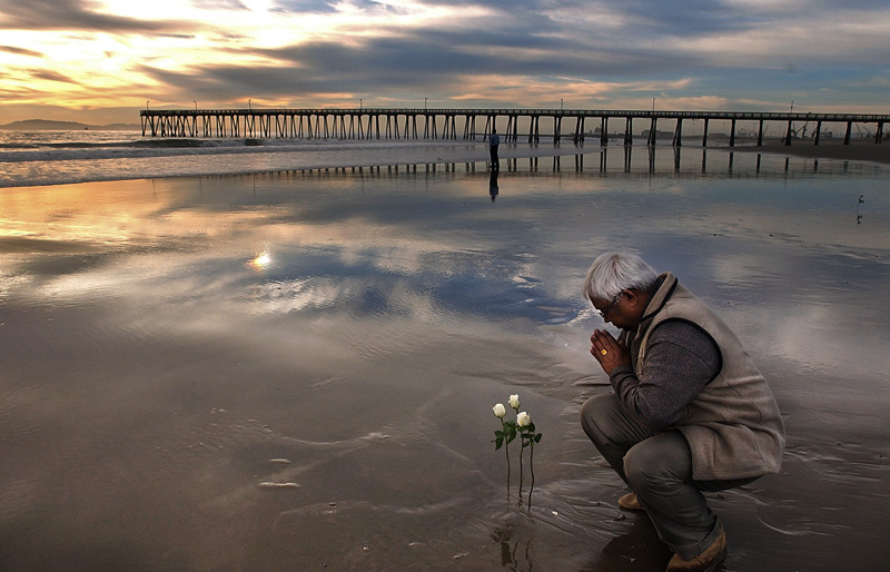 Binod Prasad prays after placing three flowers in the sand in memory of his son, Anjesh Prasad and nephews, Avinash Prasad and Amit Deo during the sixth anniversary of the fatal crash of Alaska Flight 261 in Port Hueneme, Calif. Photo by Matt McClain
