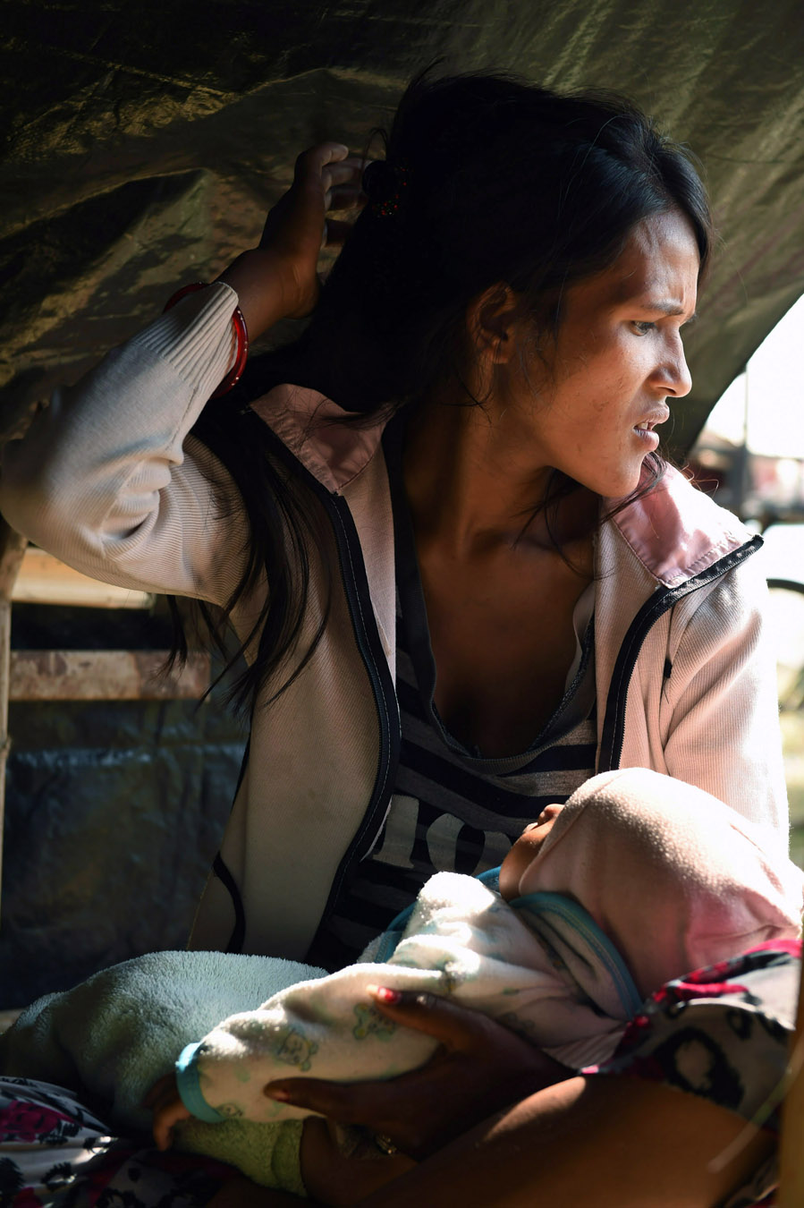 Widowed and displaced by the earthquake, Minu Nepali, 23, holds her unnamed youngest son as she now lives in a tent encampment on Tuesday May 05, 2015 in Kathmandu, Nepal. Her husband was killed in the earthquake that has killed thousands in Nepal. (Photo by Matt McClain/ The Washington Post)