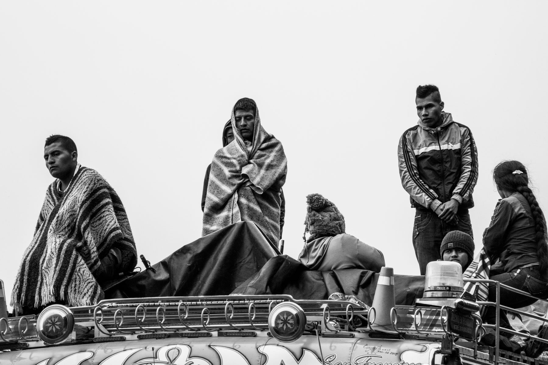 Indigenous Legacy Members of the Nasa indigenous community stand on the roof of a 'chiva' (bus) while listen to the speech of their political leader at the end of the celebration of the cleansing ritual of the 'Khabu fxizehnxi' ('Refreshing of the Batons”), one of the five main rituals of the Nasa indigenous people of the Cauca region in Colombia. The leader warns them about the threats and murders that are increasing exponentially within the territory. Cauca region, Colombia, January 2019.