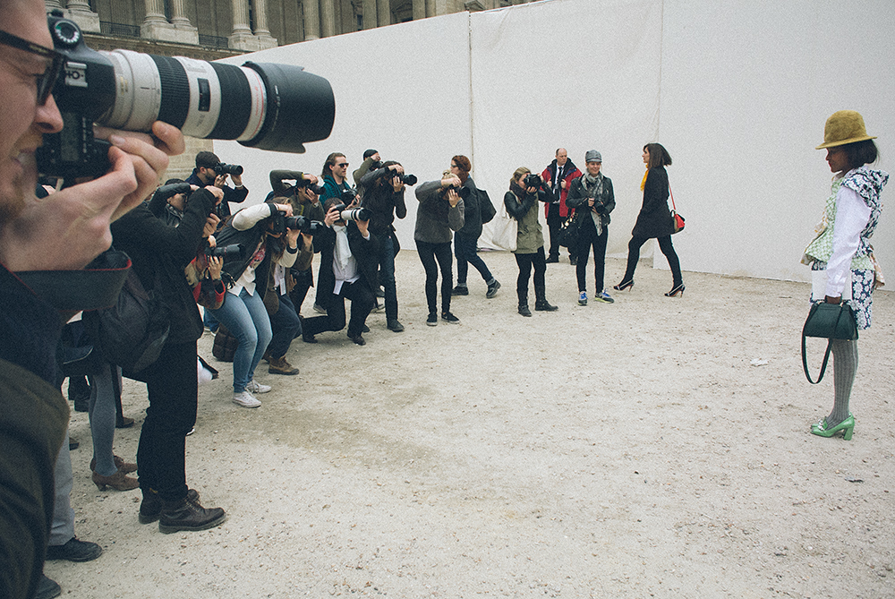 Paris. Ingresso della Cour Carrée du Louvre, prima della sfilata di Louis Vuitton. Visto il tempo a disposizione prima dell'inizio della sfilata e lo spazio, il set si allarga per fotografare l'ennesima redattrice di moda asiatica. Nell'articolo citato sopra, Suzy Menkes scrive ancora: {quote}una redattrice (o redattore) di moda è un display vivente per prodotti di marca. Più ampia è la cintura, più corta e più gonfia è la gonna, più eccentriche sono le scarpe, meglio è. La folla intorno a loro chiede e tweetta all'impazzata: di chi è quello che indossi? Hai cambiato il tuo vestito dopo l'ultima sfilata?{quote}/////Paris. Entrance to the Cour Carree of Louvre, before the Louis Vuitton show. Given the time available before the start of the show and the space, the set expands to photograph yet another Asian fashion editor. In the article cited above, Suzy Menkes also writes, {quote}the designer and fashion editor is a walking display for designer goods: The wider the belt, the shorter and puffier the skirt, the more outré the shoes, the better. The crowd around her tweets madly: Who is she wearing? Has she changed her outfit since the last show?{quote}