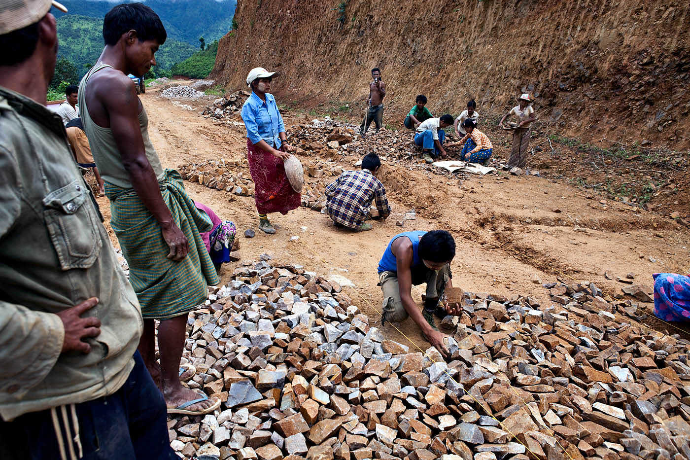 Laborers lay a base course of rough stone to the Namshan – Hsipaw road.  The road is the main artery for transporting tea south to the larger markets of Mandalay and Yangon.  Unpaved the majority of way, the short journey can easily take six hours in the dry season, and much longer during the rainy season when the road becomes prone to landslides. 